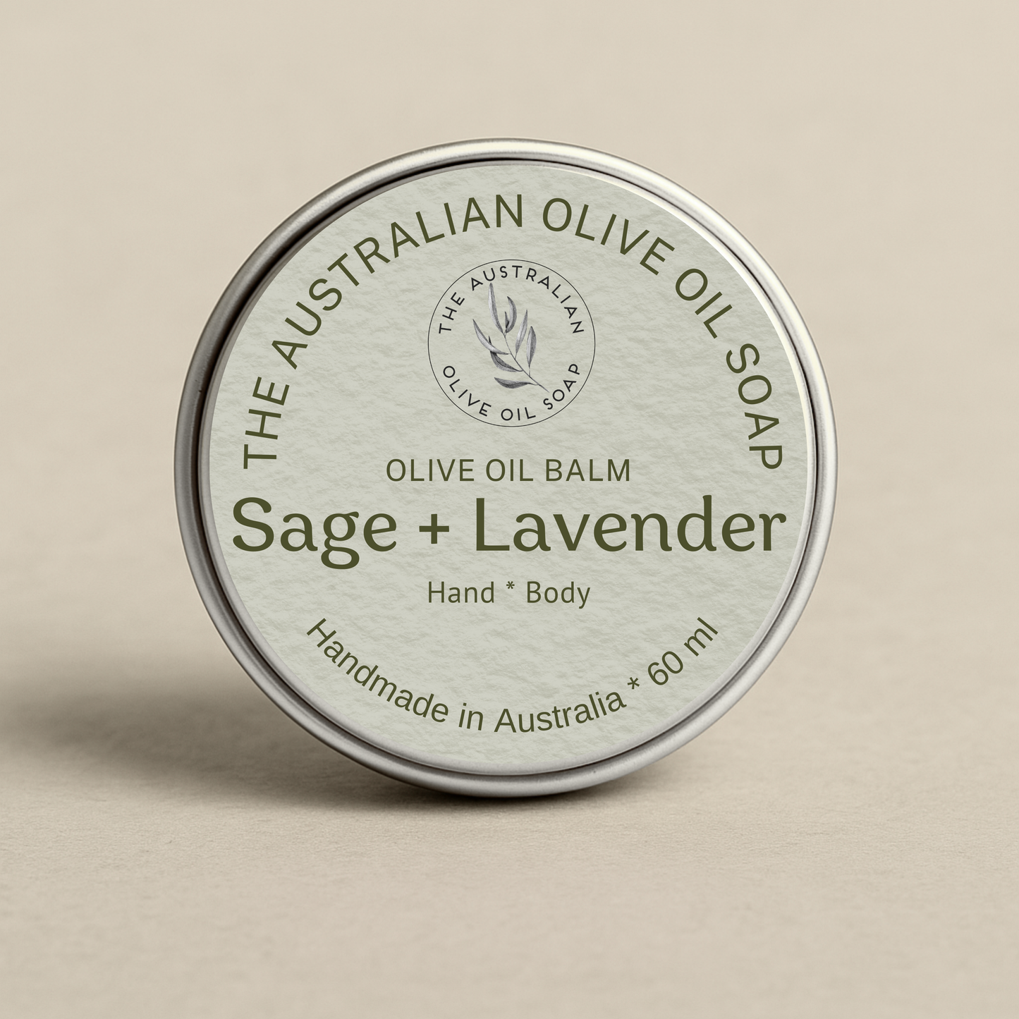 Olive oil balm tin labeled 'Sage + Lavender' from The Australian Olive Oil Soap on a beige background