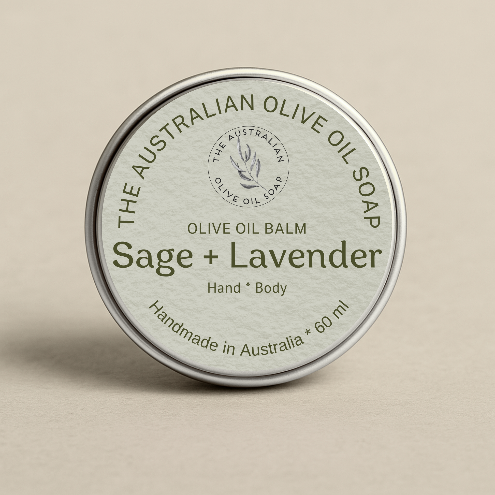 Olive oil balm tin labeled 'Sage + Lavender' from The Australian Olive Oil Soap on a beige background