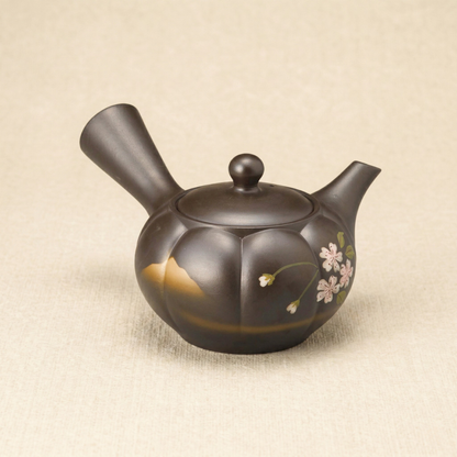 Ceramic teapot with floral designs on a beige fabric background