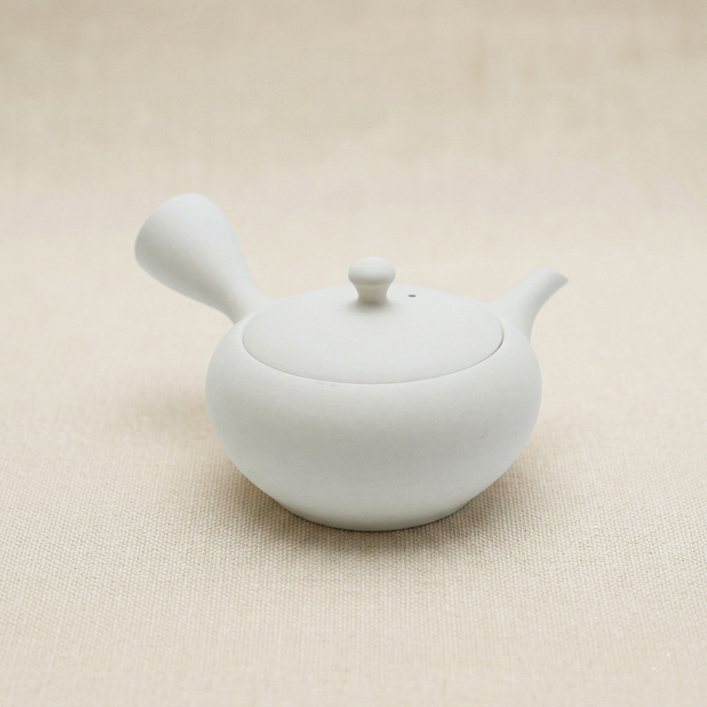 White ceramic teapot on a beige background