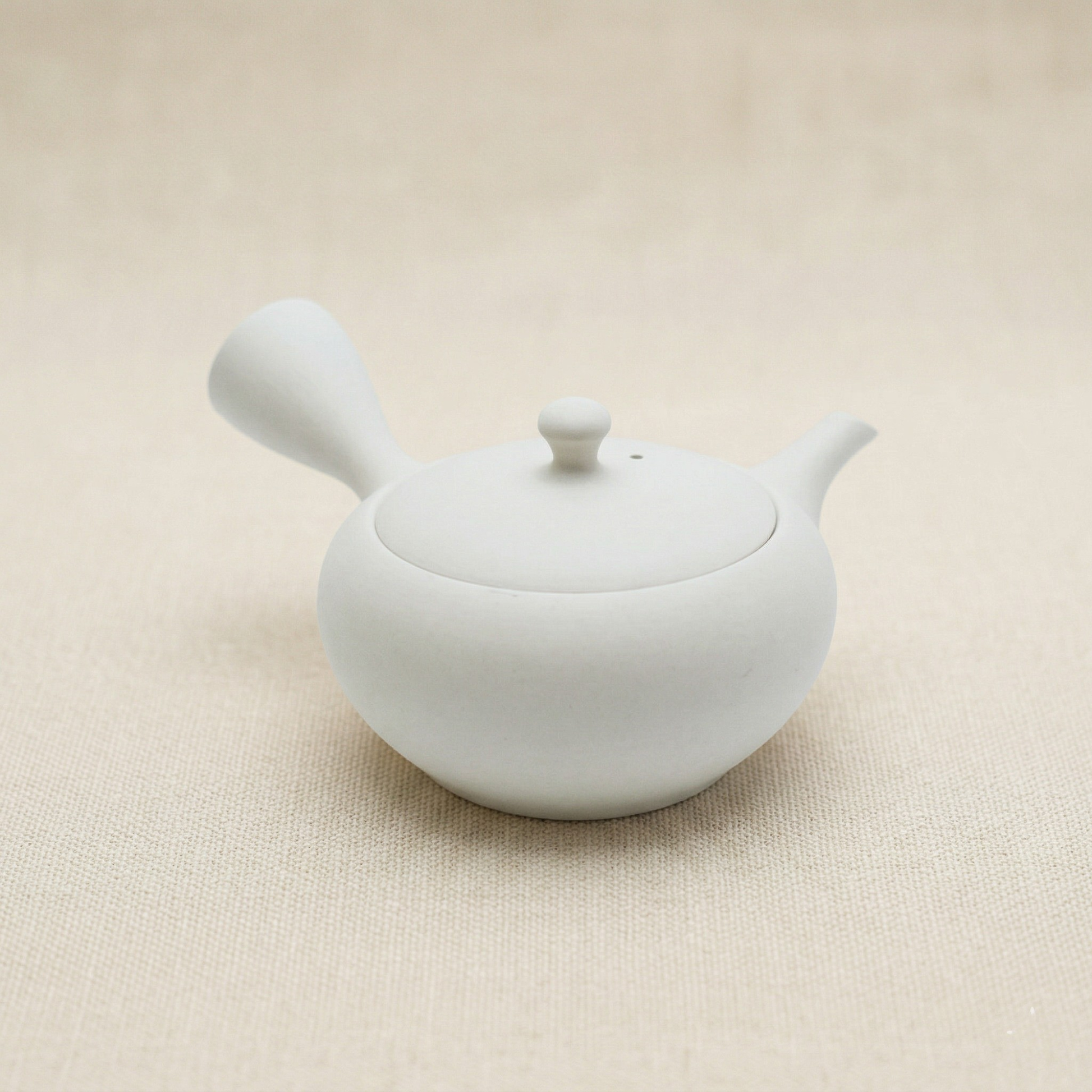 White ceramic teapot on a beige background