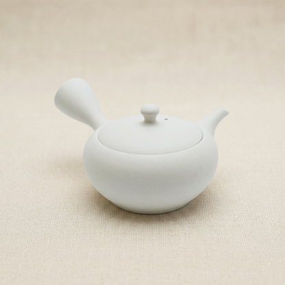 White ceramic teapot on a beige background